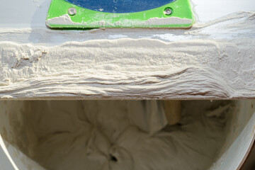 Gypsum plaster on a long steel spatula on a bucket