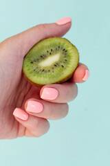 Hand with pink manicure with bright kiwi. Isolated on a classic blue background.