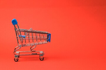 Shopping cart isolated on bright orange background. Close-up. Sale concept