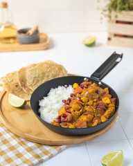 Chicken curry Indian cuisine dish with rice and naan bread in black pan on white background 