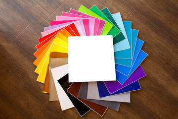 Twisted pile of colorful 12x12 sheets of adhesive paper with box isolated over the brown background. Mockup.