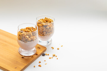 muesli with yogurt in a glass on a wooden board, free space