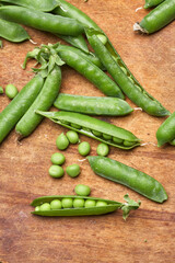 Fresh green peas pods on a wooden board.