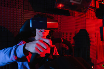 Fototapeta na wymiar concentrated guy in vr headset racing on car simulator