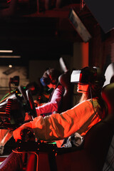Fototapeta na wymiar teenage friends in vr headsets gaming on car racing simulators