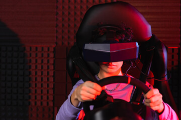 teenage guy in virtual reality headset racing on car simulator