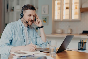 Smiling guy listening attentively online lesson while sitting at home