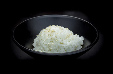 Japanese rice topped with white sesame on black bowl.