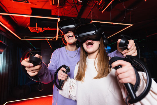 thrilled teenage gamers in vr headsets having fun in play zone - Powered by Adobe