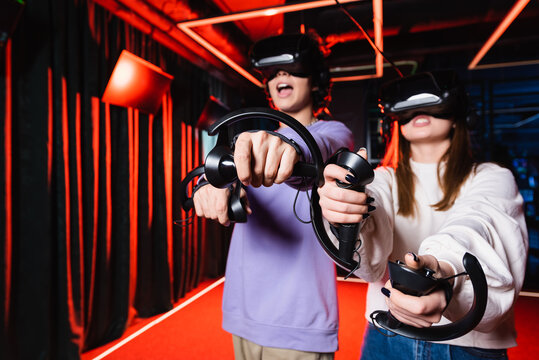 thrilled teenage gamers in vr headsets having fun in play zone