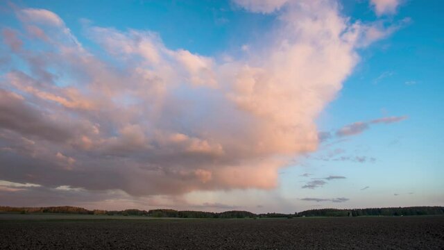 Time-lapse of rain clouds and a rainbow in the sunset. Moon and blue sky appearing.