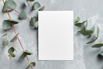 Stylish wedding invitation card mockup with eucalyptus branches on grey stony background