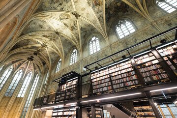 Interior of Dominican church converted into a bookstore with restaurant, customers, cathedral ceilings and pillars of the church in Maastricht, Netherlands 