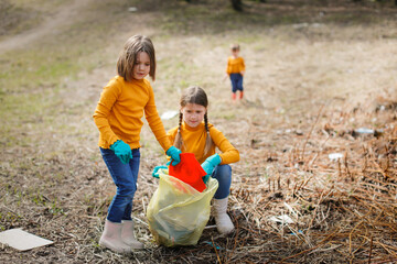 Young girl child with friends picking up trash in the park. Volunteer concept, Children picking up trash with group of volunteers in the park, forest