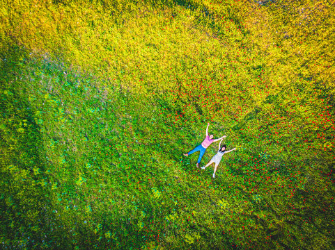 Top view couple laying together happy outdoors in green summer field outdoors. Wellness and freedom concept background
