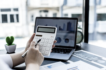 A woman pressing a white calculator with her hand, a female financial businesswoman keeping accounting, finance, taxes, and salaries for employees and Company expenses. Company financial management.
