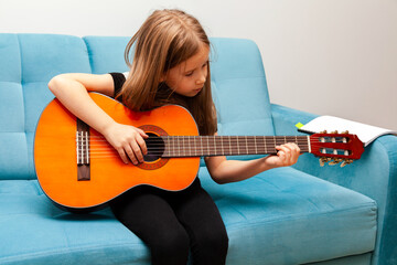 Little girl, young school age child playing guitar, focused kid practicing musical instrument...