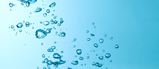 Blue bubbles under water flowing up to the surface in nature. Blue background with copy space