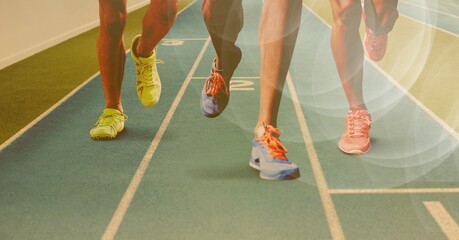 Composition of legs of running athletes on racing track with spots of light