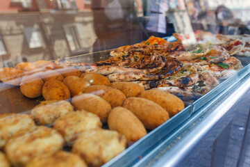 Vetrina da vendita di una pizzeria con arancini di riso, frittatine di pasta, crocchè di patate e pizze ripiene al forno