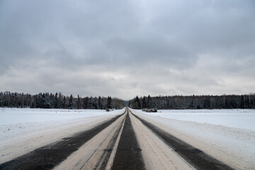 Road in the countryside in winter with forest with trees needles on the background