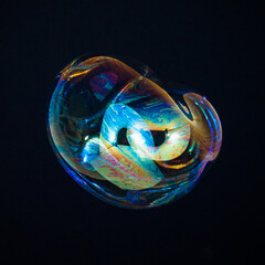 Amorphous and colorful isolated soap bubble with black background.