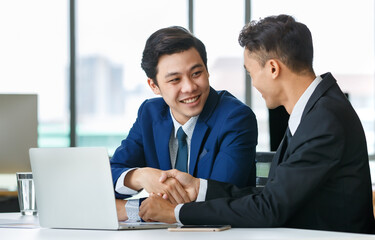 Cheerful Asian businessmen shaking hands in office