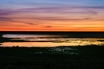 Sunset over the grassland between the dike and the wetlands.