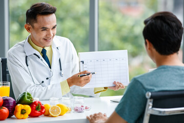 Friendly Asian nutritionist showing table to patient