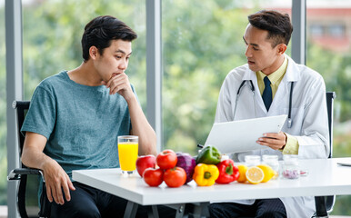 Friendly Asian nutritionist showing table to patient