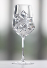 Wineglass with ice cubes on table