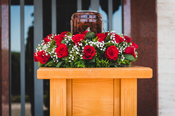 Funerary urn with ashes of dead and flowers at funeral.