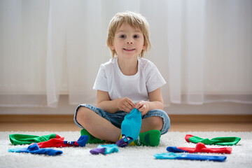 Child learning how to put in pairs different socks, kid sitting on the floor and playing with socks