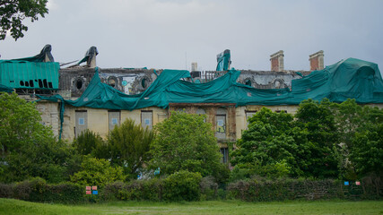 Old, torn down building in a park with tarp on the roof, almost in ruins