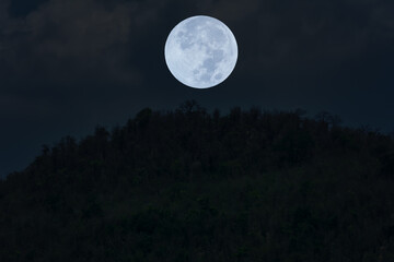 Fototapeta na wymiar Full moon on the sky over mountain silhouette.