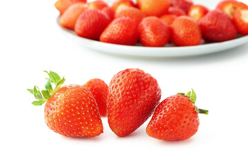 Red bright strawberry with shadows in a close-up on the background of a plate with berries, isolated