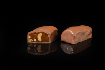 Chocolate candies on a dark background with reflection. Piece by piece and as a whole. Filling of nuts and fruits.