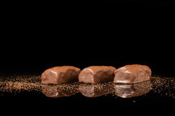 Chocolate candies on a dark background with reflection. Piece by piece and as a whole. Filling of nuts and fruits.