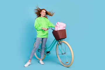 Photo of charming carefree young woman wear green sweatshirt driving bike smiling isolated blue...