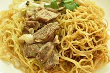 Chinese yellow egg noodles topping braised pork on plate