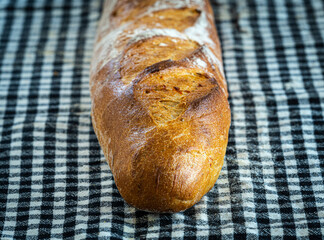 Fresh and crispy baguette on a black gingham napkin