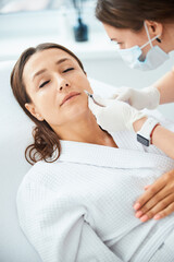 Qualified dermatologist reducing the patient nasolabial folds