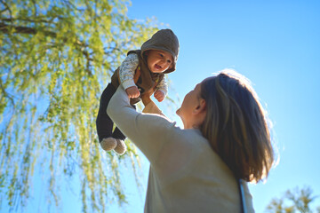 Silhouette of mother and baby at sunset. Mother throwing child up in the air. . High quality photo