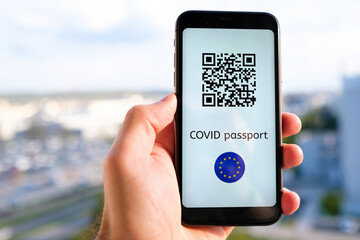 Covid pass with QR code with European Union flag on the screen in smartphone in mans hand on the background of cityscape, May 2021, San Francisco, USA.