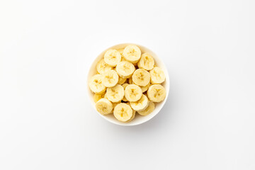 Many banana slices in white bowl. Top view