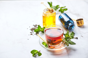 Black tea in glass transparent mug with mint leaves and honey. Calming and revitalizing tea, anti-stress and relaxation