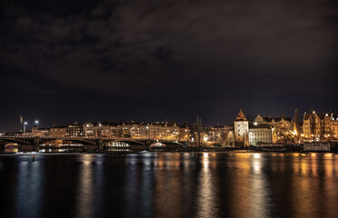 Obraz na płótnie Canvas A night shot of Prague from Slavonic Island - Slovansky ostrov - over Vltava and towards Smichov and Jirásek Bridge - Jiraskuv most