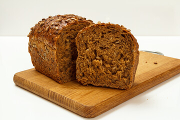 Cut loaf of bread on wooden cutting board on white background