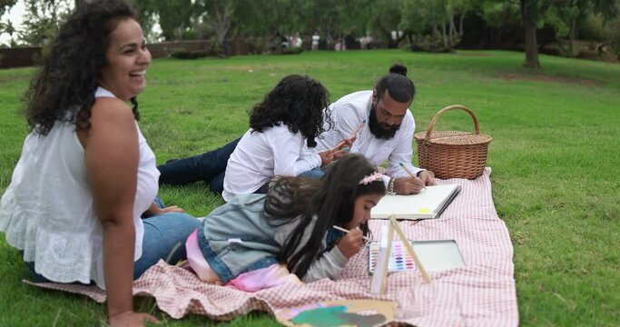 Indian parents having fun at city park painting with their children - Family, summer and love concept 