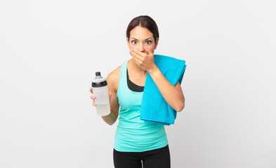 young hispanic woman covering mouth with hands with a shocked. fitness concept
